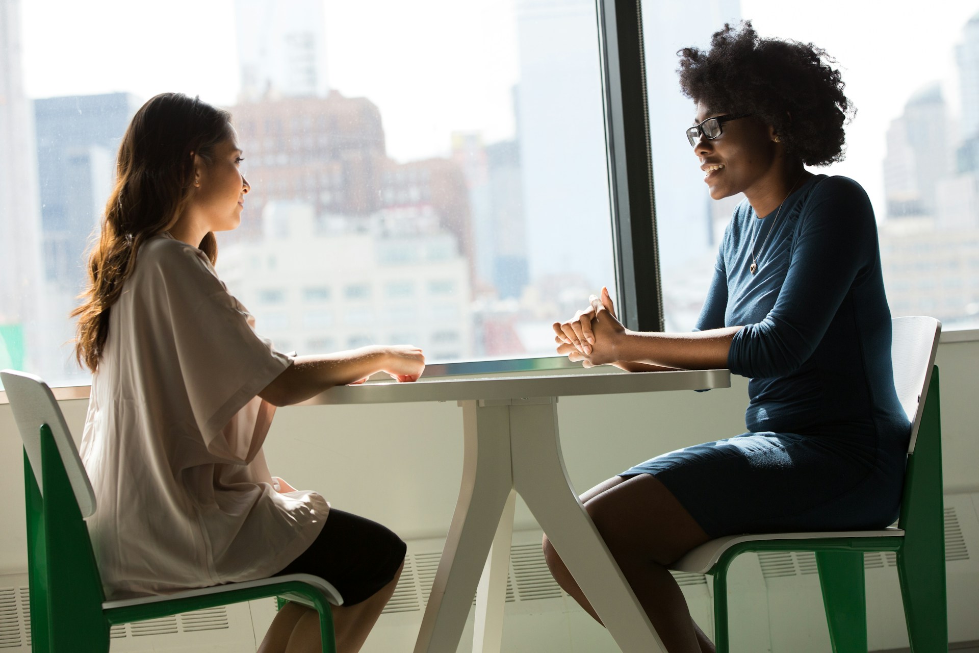 Two people sitting at a table talking with one another